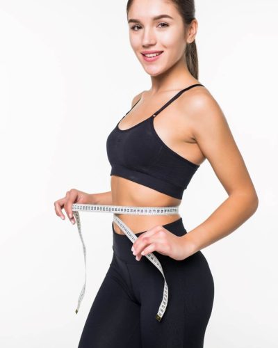 young-fitness-woman-measure-with-tape-her-belly-isolated-white-wall